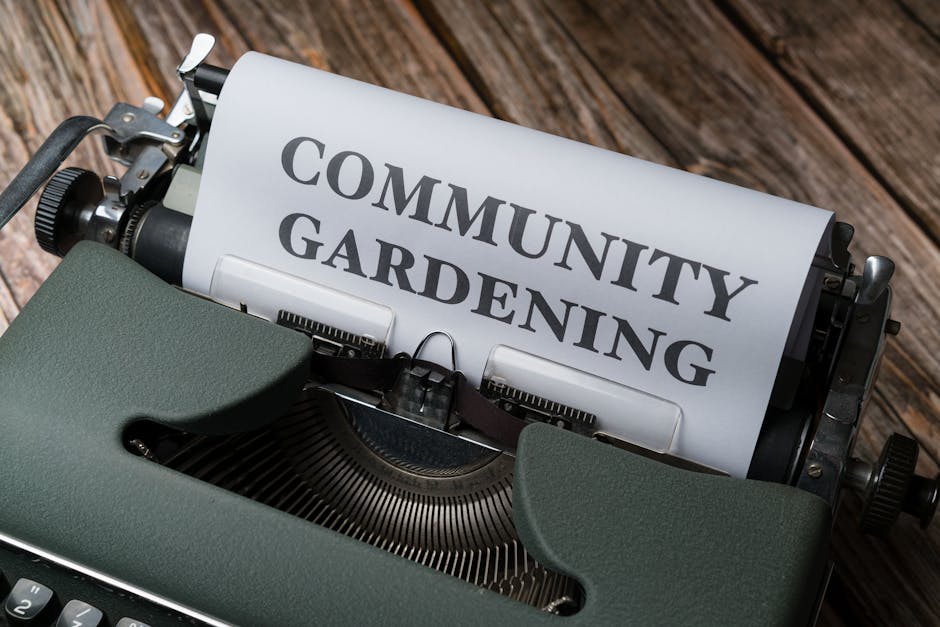 A close-up view of a vintage typewriter with a sheet of paper inserted, displaying the words 'COMMUNITY GARDENING' in bold, black font. The typewriter is placed on a wooden surface, with visible textu